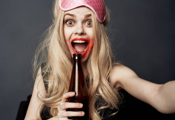 酔った女性とともにビールボトルの上に灰色の背景ジェスチャーで彼女の手と明るいメイク - 写真・画像