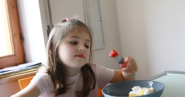 chica y caras divertidas y pastel de fresas en la cocina - Imágenes, Vídeo