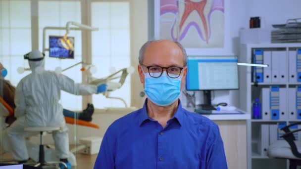 Портрет пожилого человека в маске в стоматологическом кабинете, смотрящего в камеру - Кадры, видео