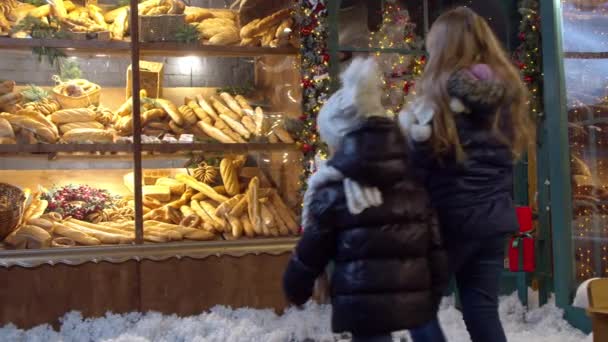 Meisjes onderzoeken brood in bakkerij venster op kerstdag - Video