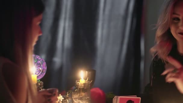 Zijaanzicht van waarzegster vrouw gebruikt taro kaarten om toekomst te voorspellen aan haar jonge vrouwelijke cliënt - Video