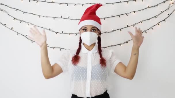 Junges Mädchen mit rotem Weihnachtsmütze und Maske, sehr glücklich, tanzend, winkend und Küsschen sendend - Filmmaterial, Video