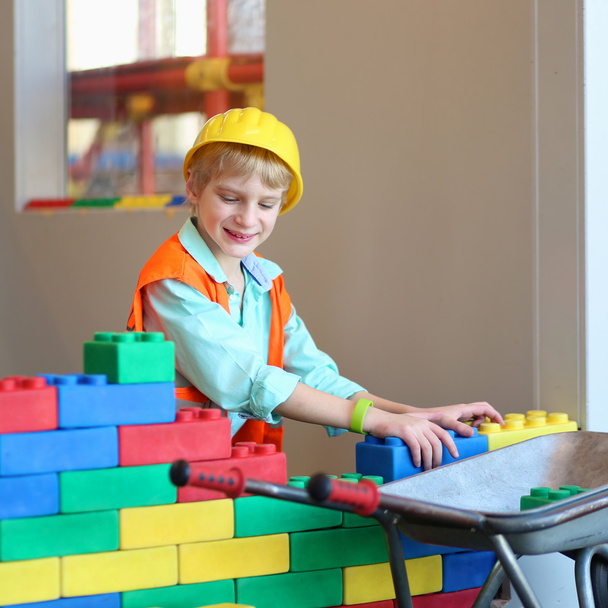 Boy building a house with big plastic construction bricks - Fotoğraf, Görsel