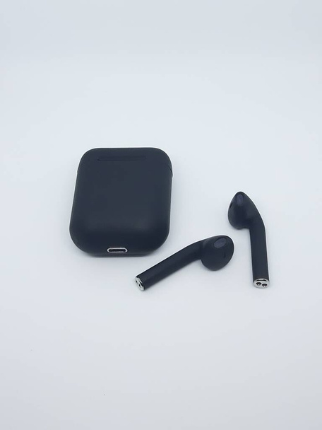 Schwarzer True Wireless Kopfhörer mit Ladegerät (TWS) auf weißem Hintergrund - Foto, Bild