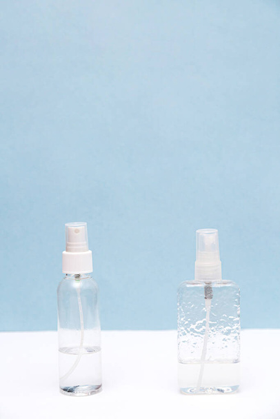 Antiseptische flessen op witte en blauwe achtergrond met kopieerruimte. Handreiniger. Gezondheidszorgconcept - Foto, afbeelding