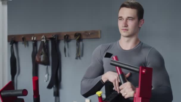 Schöner, athletischer Mann, der an Trainingsgeräten im Fitnessstudio Sport treibt - Filmmaterial, Video