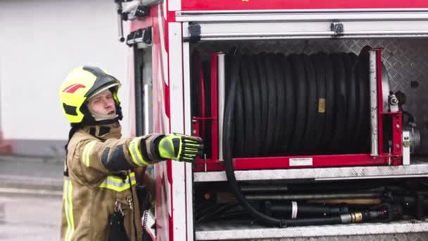 Pompier debout devant le camion de pompiers prêt à dérouler le tuyau - Séquence, vidéo