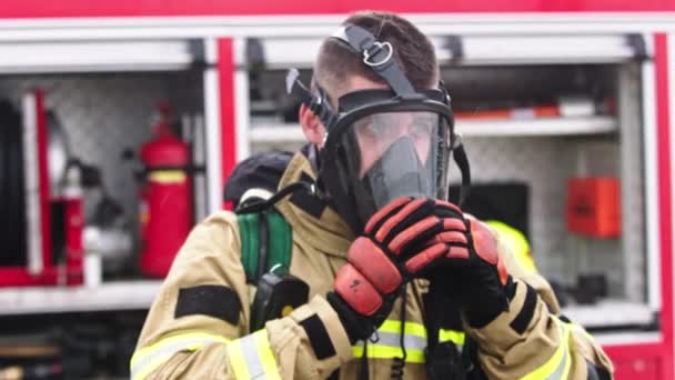 Firefighter removing gas mask from hs face in front of the firetruck - Footage, Video
