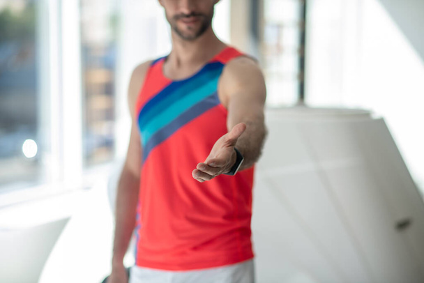 Sporty man in bright tshirt outstretching his arm - Фото, зображення