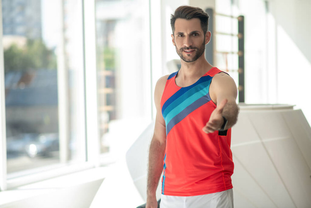 Sporty man in bright tshirt standing with an outstretched arm - Fotografie, Obrázek
