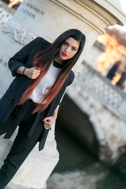 beautiful brunette long haired girl posing in jacket and black pants in padua. High quality photo - Photo, Image