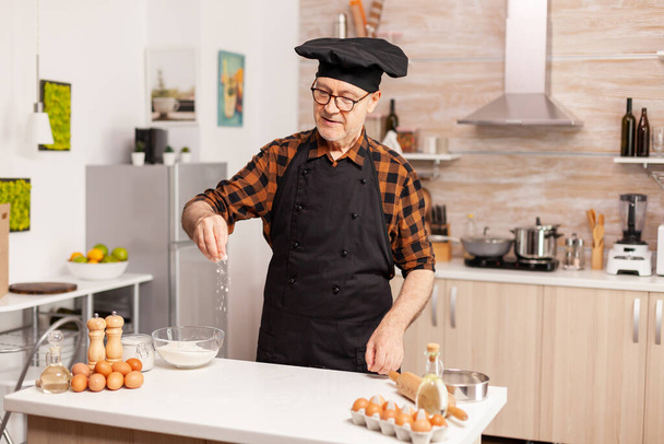 Senior bakker in huis keuken zetten tarwe - Foto, afbeelding