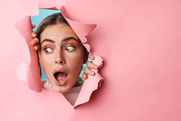 Caucasian young excited woman screaming and looking at copyspace through pink background isolated closeup - Valokuva, kuva