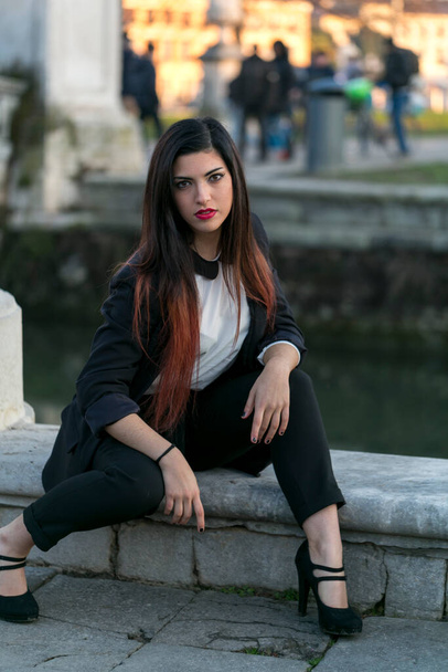 beautiful brunette long haired girl posing in jacket and black pants in padua. High quality photo - Fotografie, Obrázek