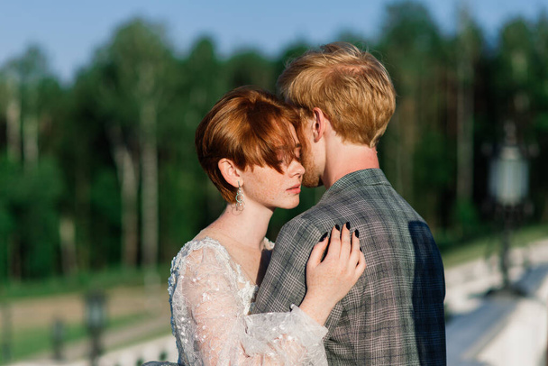 Дуже гарна руда молода просто вийшла заміж щаслива пара цілується на заході сонця на відкритому повітрі
 - Фото, зображення