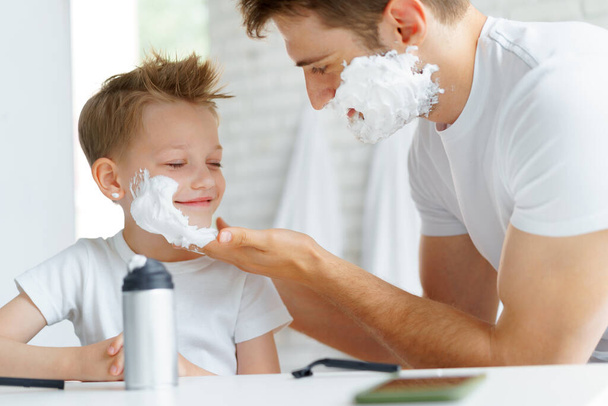 Father teaches his little son how to shave face - Foto, afbeelding