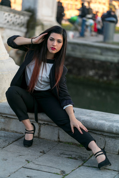 beautiful brunette long haired girl posing in jacket and black pants in padua. High quality photo - Foto, imagen