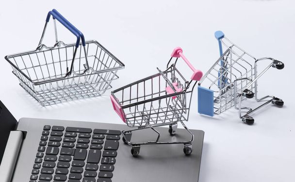 Online-Shopping. Laptop mit Einkaufswagen, Korb auf weißem Hintergrund. - Foto, Bild