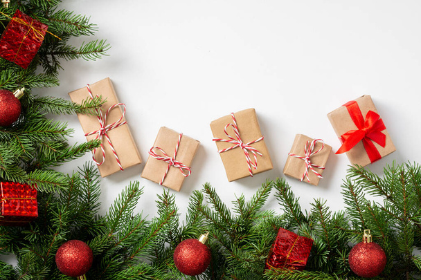 Gift boxes in craft paper. Christmas background. Christmas gifts under spruce branches decorated with wooden ornaments on a white background. Copyspace - Φωτογραφία, εικόνα