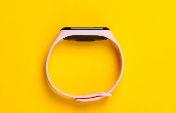 Smart bracelet on yellow background. Modern gadgets. Top view. Minimalism - Photo, Image
