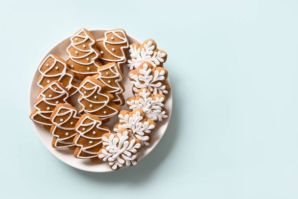 Christmas gingerbread cookies in plate on light blue background. Merry Christmas and Happy New Year greeting card with copy space. View from above. - Foto, Imagen
