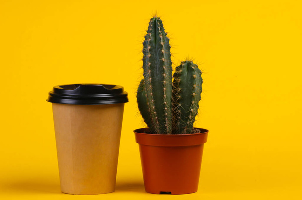 Cactus in pot and coffee cup on a yellow studio background. Minimalism - Zdjęcie, obraz