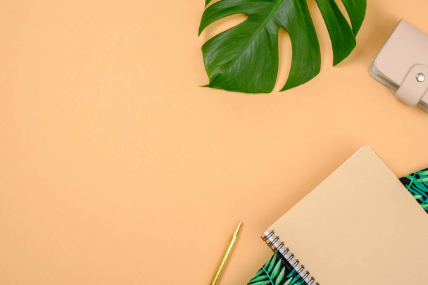 Flat lay traveler accessories on yellow background with copy space. Top view tropical monstera leaf, purse, paper notebook, pen. Summer background. Travel vacation concept. - Fotó, kép