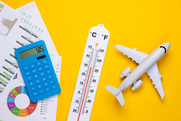 Global warming concept. Climate control. Air travel. Graphs and charts, weather thermometer, calculator, plane on yellow background. Top view. Flat lay - Foto, Imagem