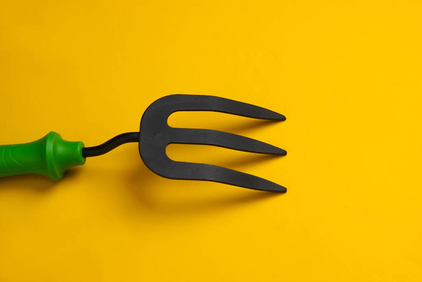 Mini garden fork on a yellow studio background. - Photo, Image
