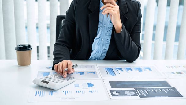 Business nainen ovat numeerisia tietoja kaavion avulla laskin, investointikartta käyttäen laskin hänen toimistonsa työpöydällä tarkastelemalla  - Valokuva, kuva
