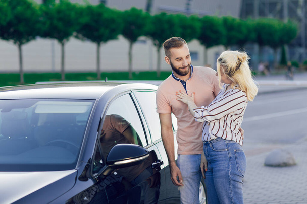 Happy young couple, man and woman inspect a new car. Car sale. Buying a new car. - Φωτογραφία, εικόνα