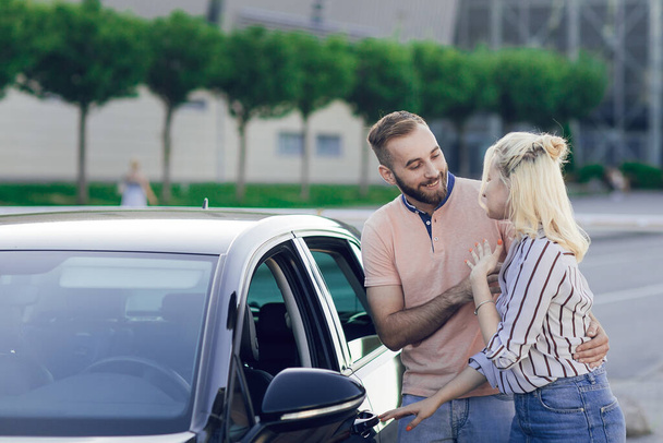 Happy young couple, man and woman inspect a new car. Car sale. Buying a new car. - Photo, Image