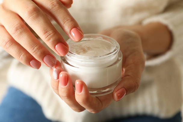 Woman in sweater and jeans hold jar of cosmetic cream - Foto, Bild