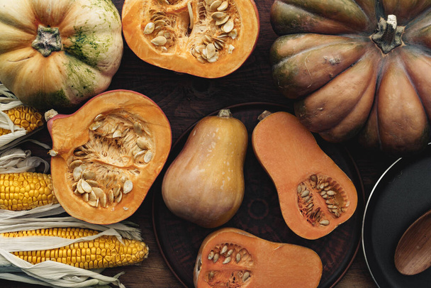 Corn cob and pumpkin on brown wooden board - 写真・画像