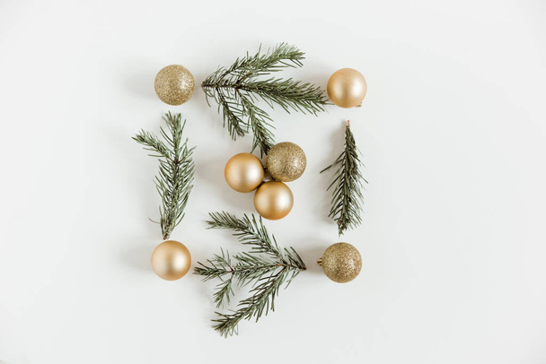Χριστούγεννα επίπεδη θέσει με έλατο κλαδιά πεύκου και χρυσά μπάλες Χριστουγέννων στο λευκό φόντο. Μινιμαλιστικό σκανδιναβικό στυλ. - Φωτογραφία, εικόνα