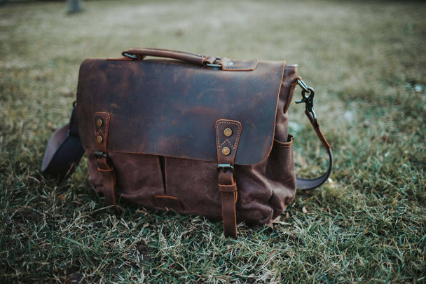 A closeup shot of an old and classic sling bag left on the ground - Zdjęcie, obraz