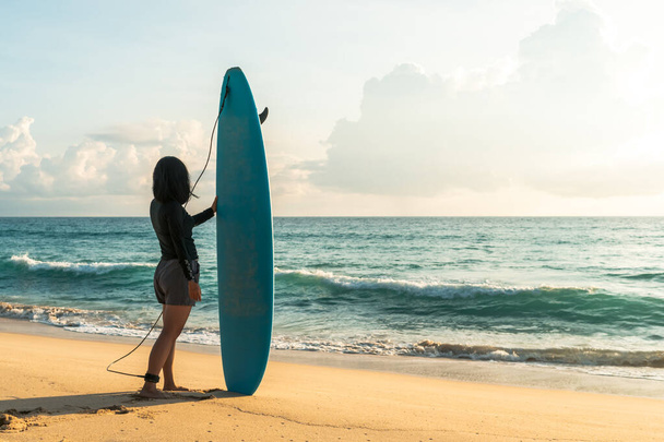 Surfista mulher carregando suas pranchas de surf na praia do pôr do sol com fundo de luz solar - Foto, Imagem