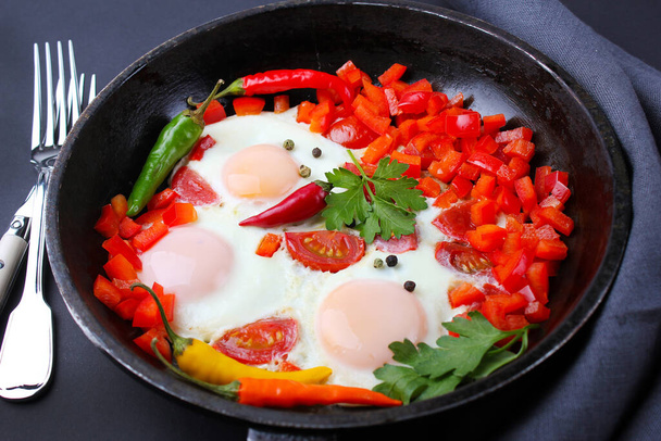 scrambled eggs  with peppers and tomatoes in a pan. - 写真・画像