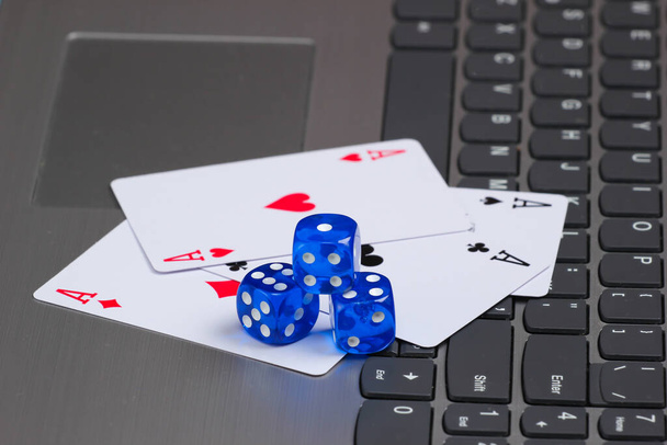 Vier Asse spielen Karten und blaue Würfel auf einer Laptop-Tastatur. Online Poker Casino - Foto, Bild