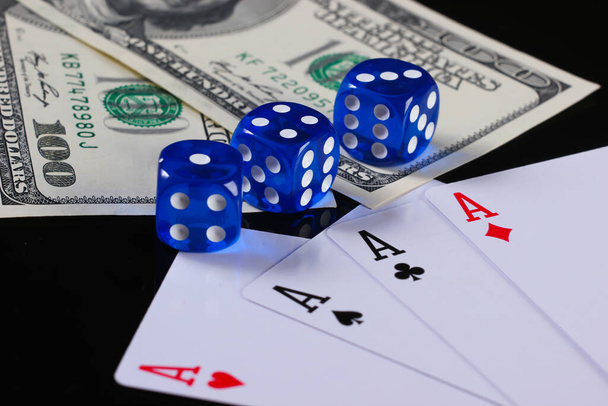 Vier Asse mit Würfeln und Hundert-Dollar-Scheinen auf schwarzem Hintergrund. Glücksspiel - Foto, Bild