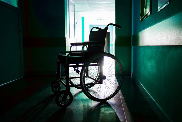 Silhouette of empty wheelchair parked in the hospital corridor - Foto, Imagem