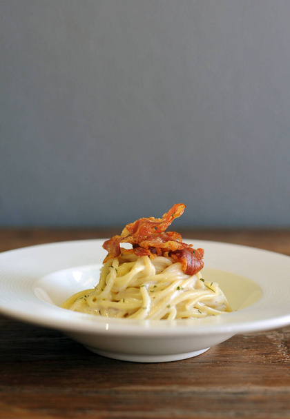 Heerlijke spaghetti carbonara met spek op houten tafel - Foto, afbeelding