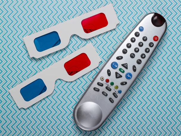 Anaglyph wegwerppapier 3d bril en tv afstandsbediening op blauwe achtergrond. Tijd voor TV. Bovenaanzicht - Foto, afbeelding