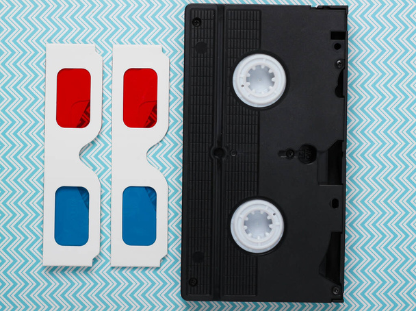80 'lerin kağıt stereo 3D gözlükleri ve video kaseti. Mavi pastel arka plan. Üst görünüm - Fotoğraf, Görsel