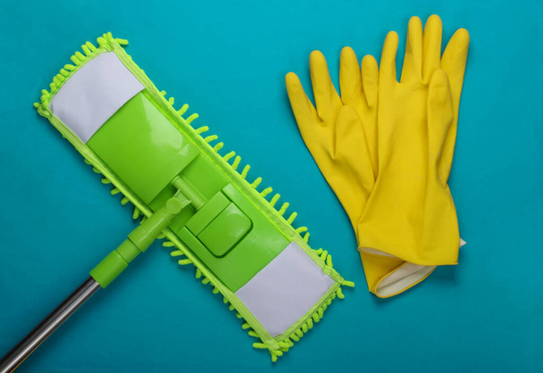 Balai en plastique vert, gants sur fond bleu. Désinfection et nettoyage dans la maison. Vue du dessus - Photo, image