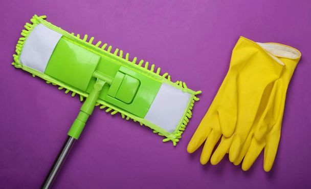Πλαστική πράσινη σφουγγαρίστρα, γάντια σε μωβ φόντο. Απολύμανση και καθάρισμα στο σπίτι. Άνω όψη - Φωτογραφία, εικόνα