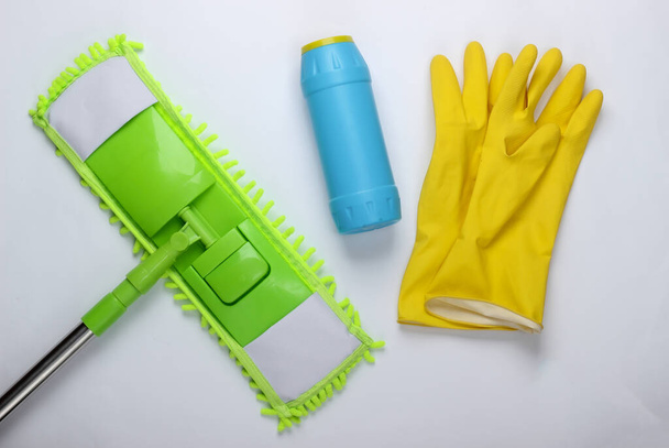 Cleaning products. Plastic green mop, gloves, bottle of detergent on white background. Disinfection and cleaning in the house. Top view - Photo, Image