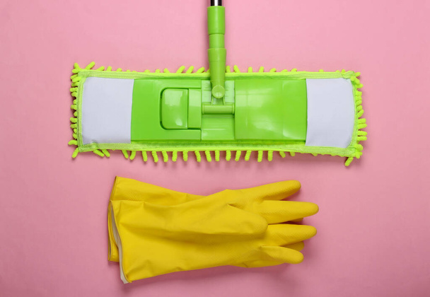 Plastic green mop, gloves on pink background. Disinfection and cleaning in the house. Top view - Photo, Image