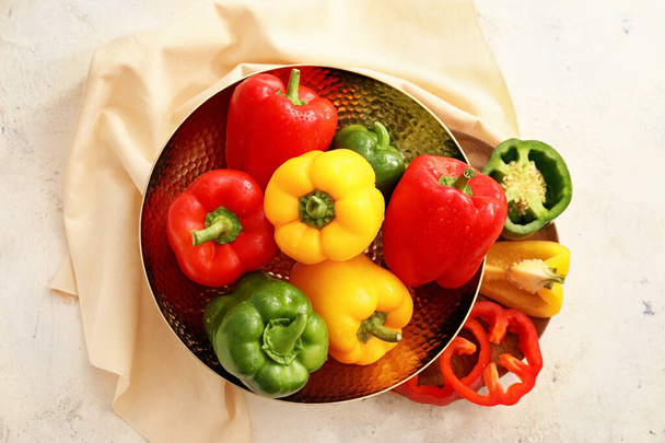 Metal bowl with colorful bell peppers on light background - Фото, зображення