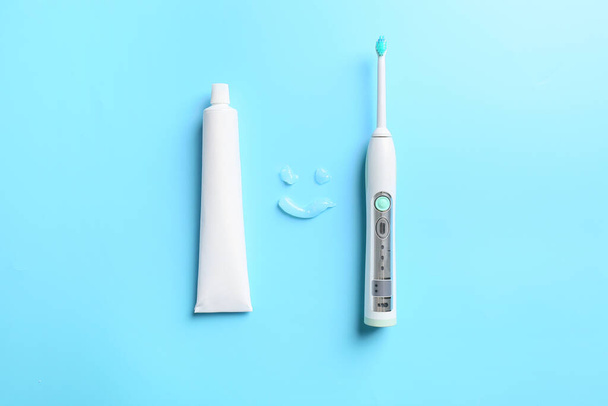 Elektrische tandenborstel en plak op kleur achtergrond - Foto, afbeelding